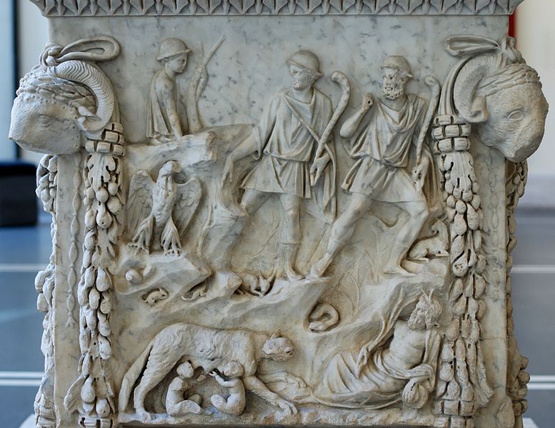 Representation of the lupercal: Romulus and Remus fed by a she-wolf, surrounded by representations of the Tiber and the Palatine. Panel from an alter dedicated to the divine couple of Mars and Venus. Marble, Roman artwork of the end of the reign of Trajan (98-117 CE), later re-used under the Hadrianic era (117-132 CE) as a base for a statue of Silvan. From the portico of the Piazzale dei Corporazioni in Ostia Antica.